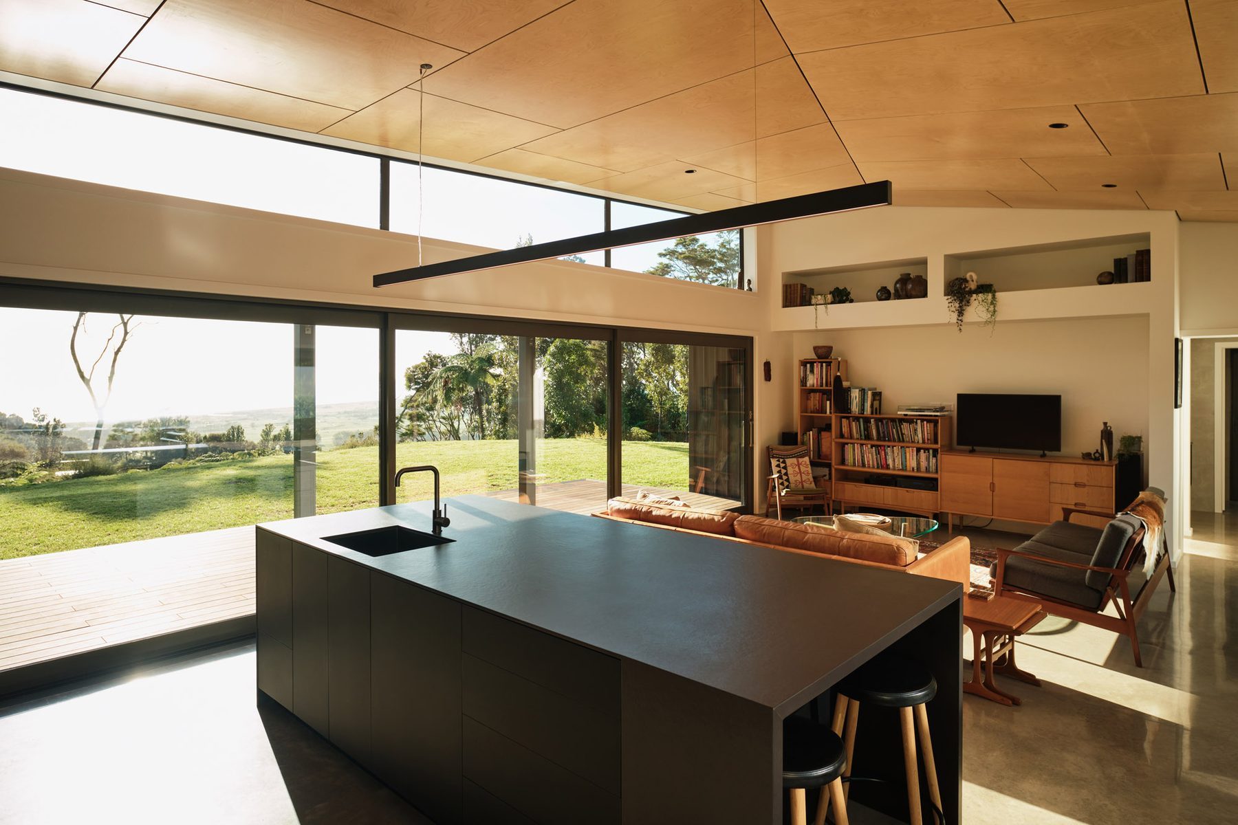 Open-plan living under the birch plywood raking ceiling.