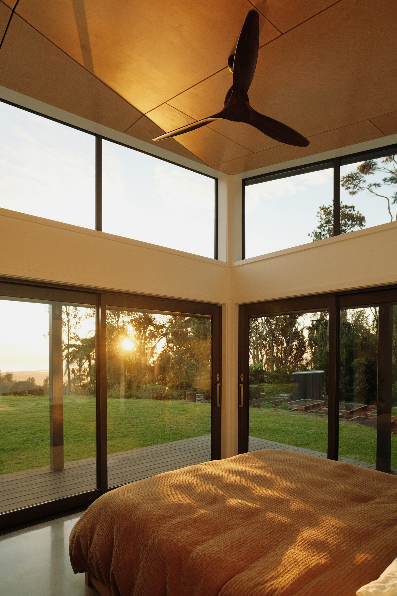 Morning light: main bedroom at sunrise with plywood ceiling lining and ceiling fan