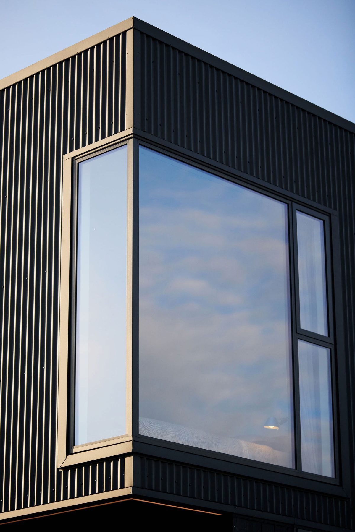 Corner window catching the sky in black corrugate.