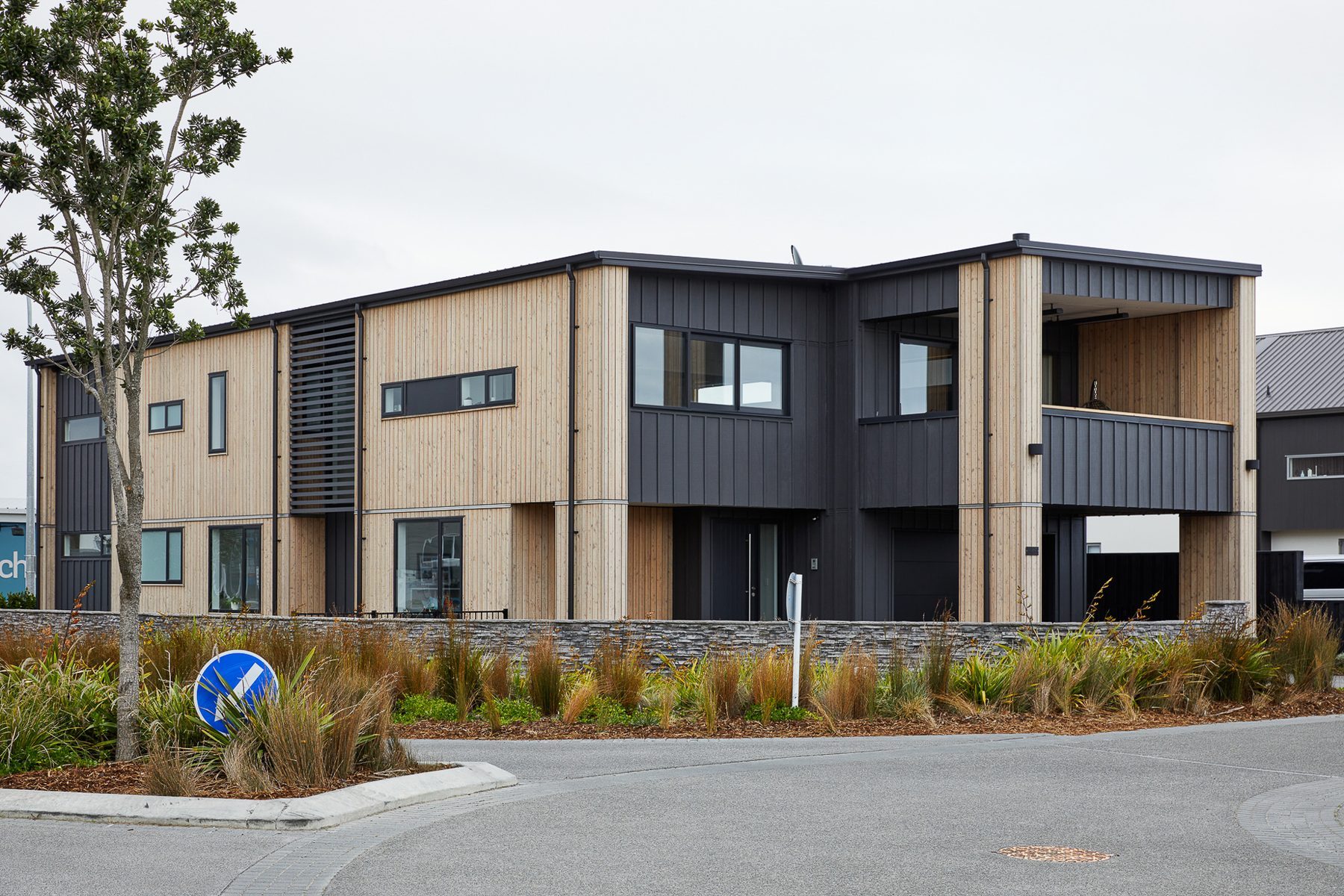 Street approach: larch and dark board-and-batten on the corner site.