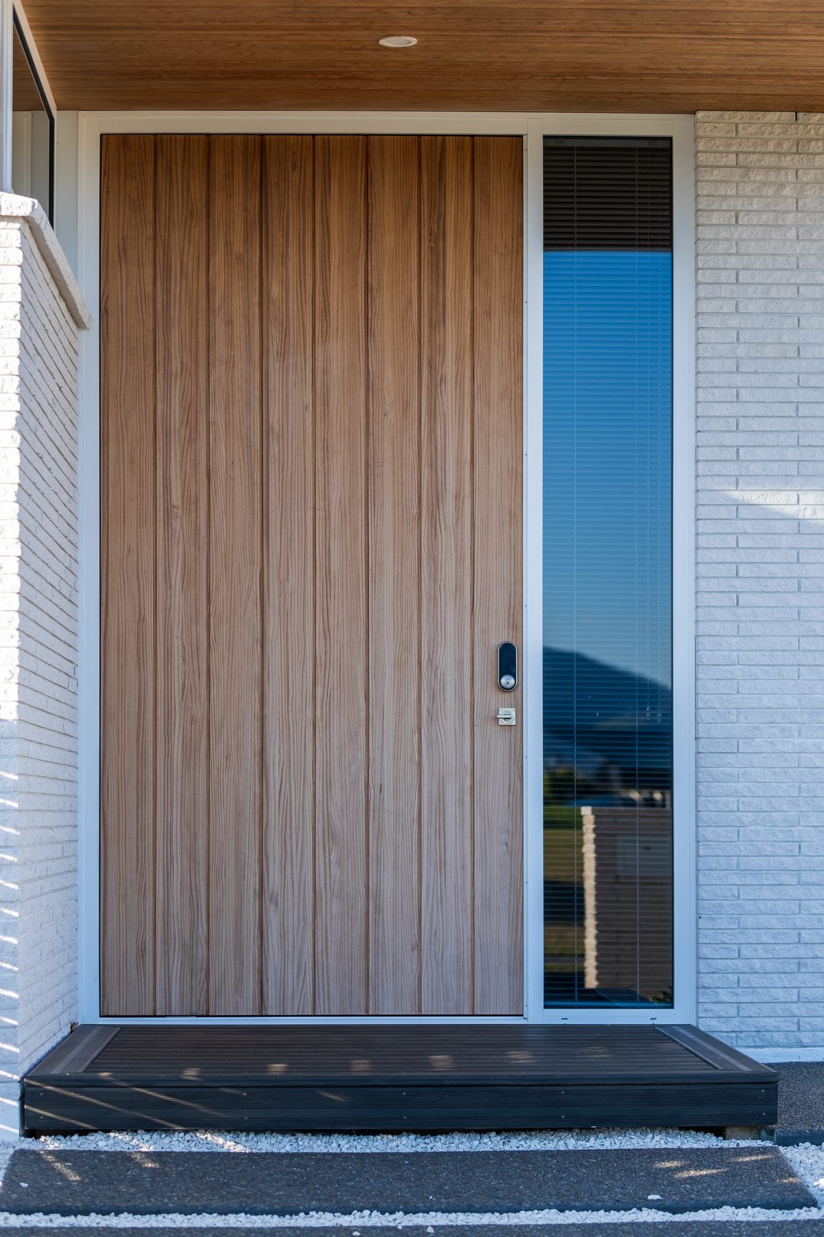 Full-height timber entry door against white brick.